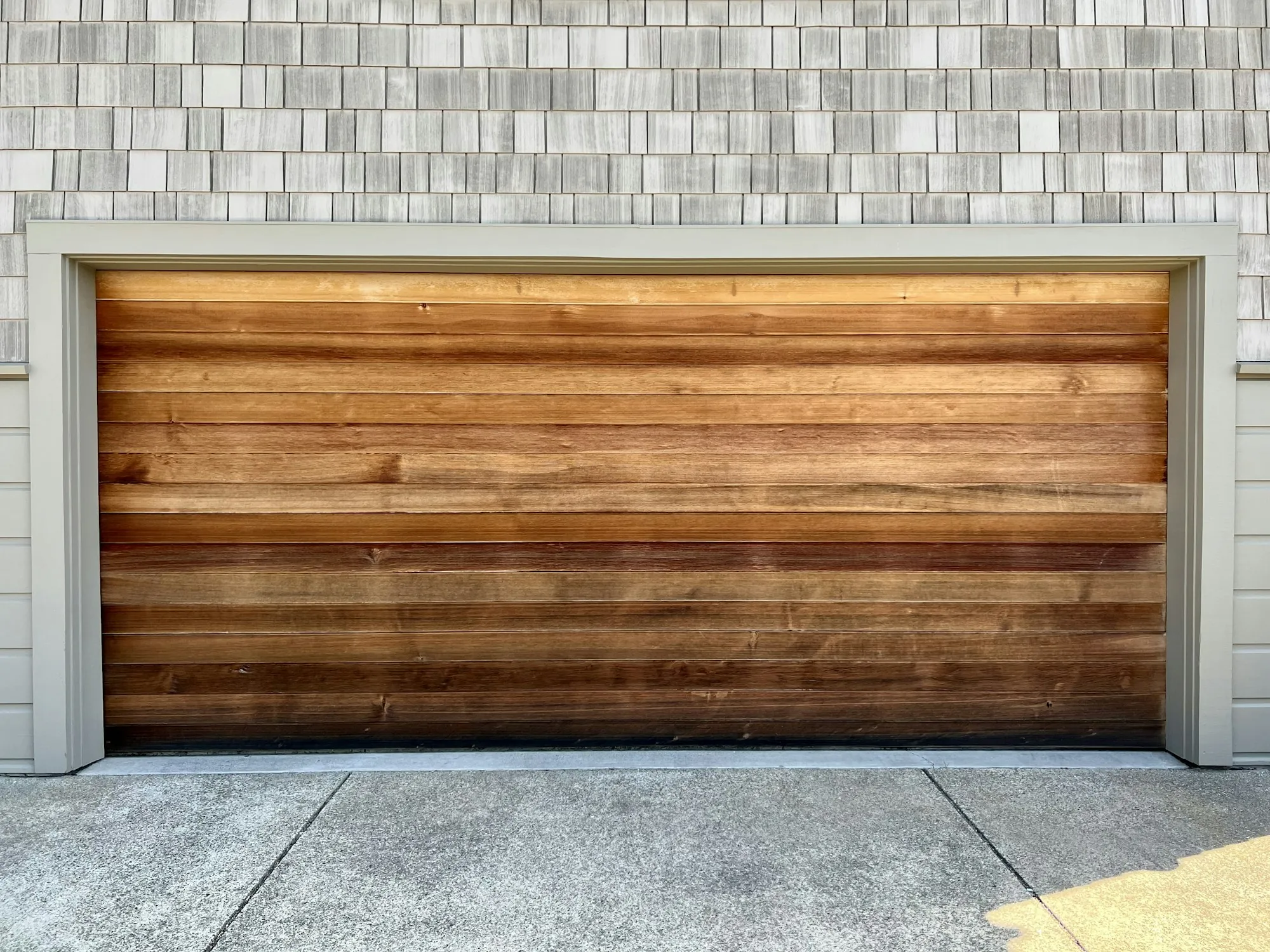 Wood-finish garage door on a shingled wall